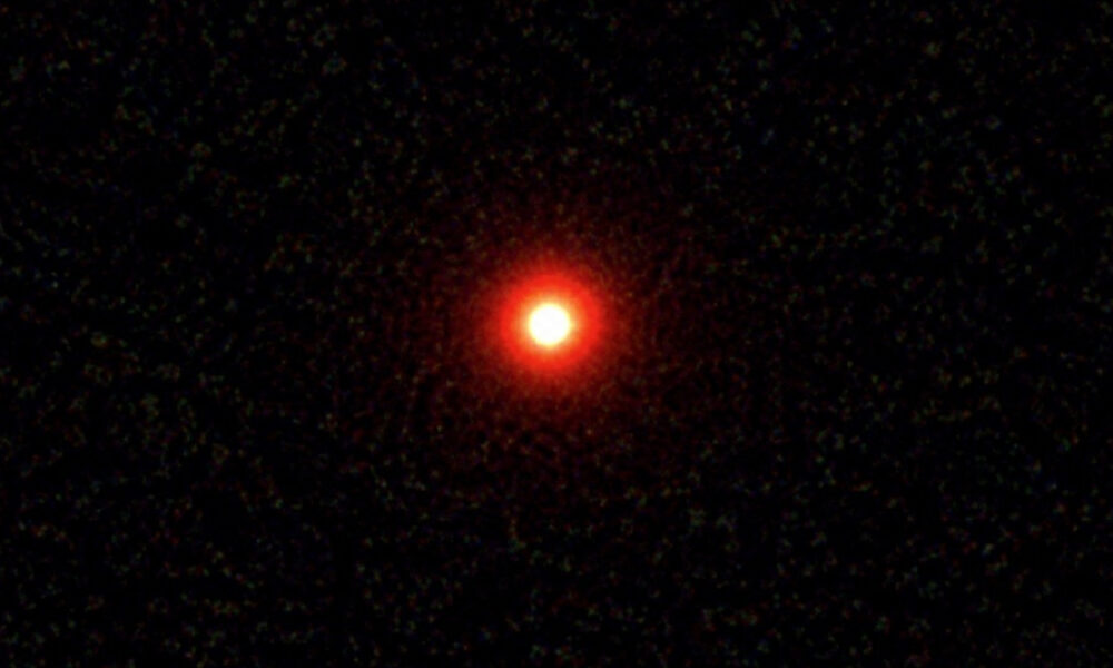 Bright red point of light in a dark starry sky (likely a star or planet).