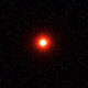 Bright red point of light in a dark starry sky (likely a star or planet).
