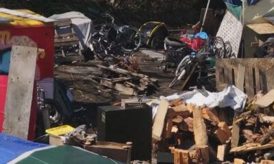 Chaotic outdoor junk pile with bikes, wood, bricks, and scattered debris in a cluttered yard.