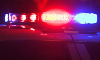 Police car with red and blue emergency lights flashing at night, reflecting off the car’s surface.