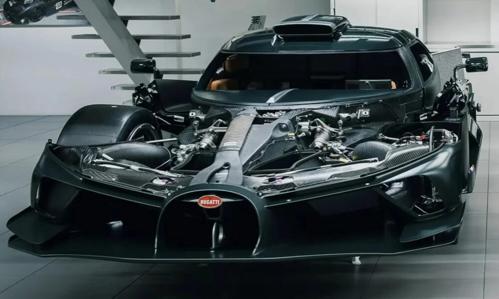 Front view of a black Bugatti supercar with its hood open, exposing the mid-mounted engine and carbon fiber components in a showroom