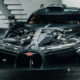 Front view of a black Bugatti supercar with its hood open, exposing the mid-mounted engine and carbon fiber components in a showroom