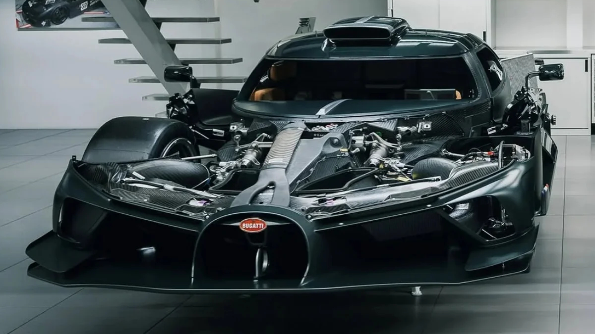Front view of a black Bugatti supercar with its hood open, exposing the mid-mounted engine and carbon fiber components in a showroom