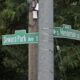 Intersection street signs on a pole reading Seward Park Ave S and Henderson St with leafy trees in the background.
