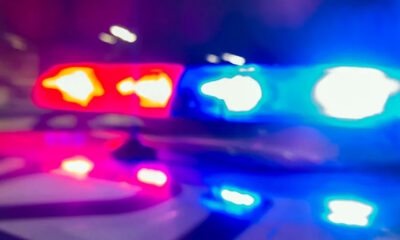 Blurred red and blue emergency vehicle lights flashing, suggesting a police car at night