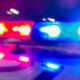 Blurred red and blue emergency vehicle lights flashing, suggesting a police car at night