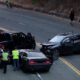 Accident scene with two damaged SUVs on a two-lane road; police and investigators in reflective vests inspect the vehicles amid scattered debris.