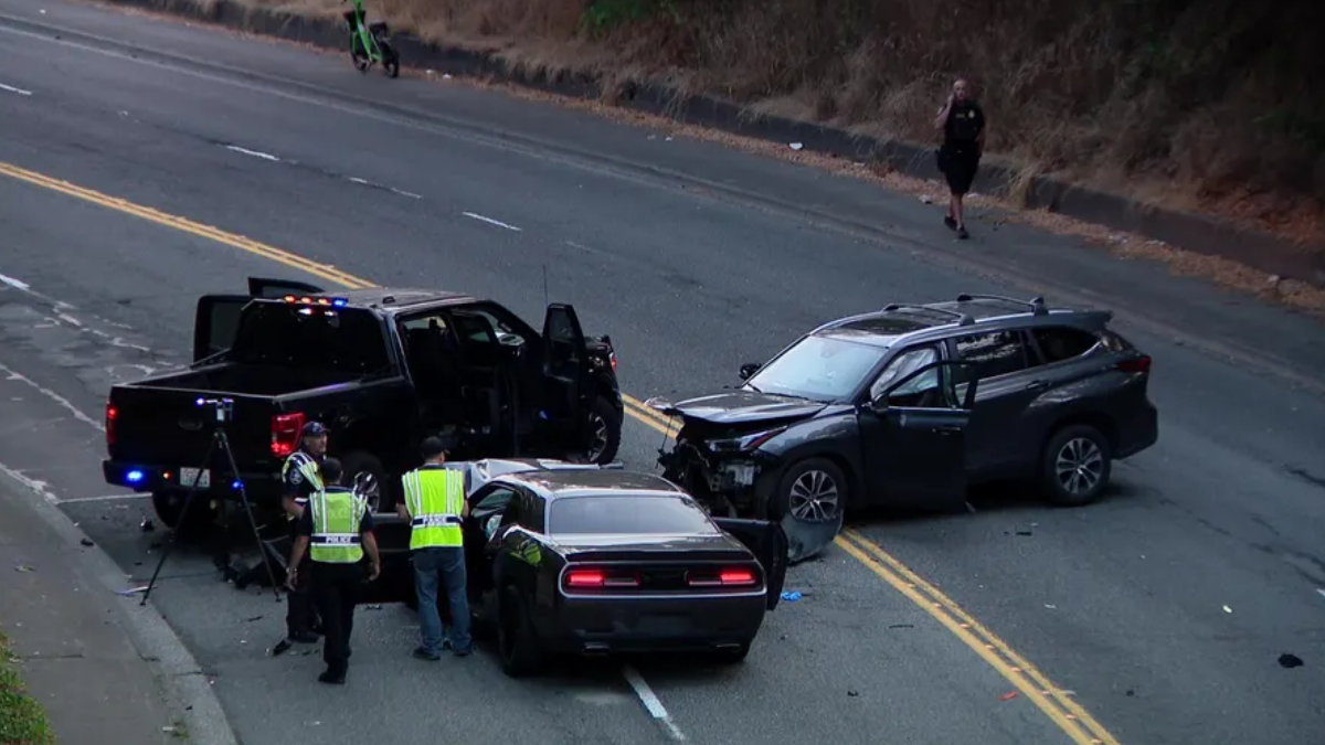 Accident scene with two damaged SUVs on a two-lane road; police and investigators in reflective vests inspect the vehicles amid scattered debris.