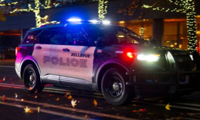 Bellevue Police SUV with flashing blue lights at night on a city street with holiday lights in the background.