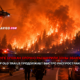 Firefighters and a helicopter battle a wildfire at night; bold Russian headline about evacuation zones expanding and the Old Trails fire spreading