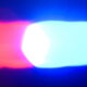 Red and blue emergency lights flashing, suggesting a police or emergency vehicle at night.