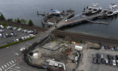 Aerial view of a waterfront dock with ferries, a pier, and a nearby construction site along the waterway