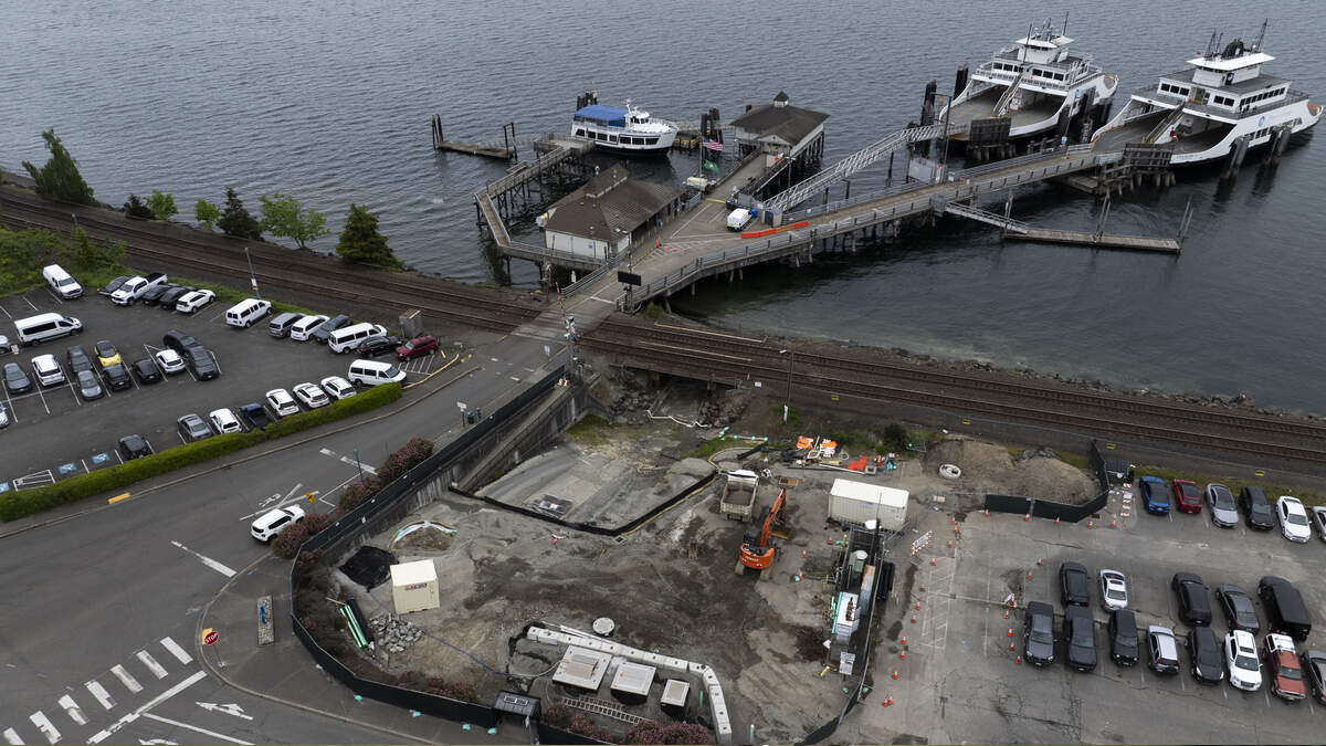 Aerial view of a waterfront dock with ferries, a pier, and a nearby construction site along the waterway