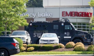 Armored SWAT vehicle parked by a hospital emergency entrance with police cars nearby