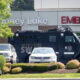 Armored SWAT vehicle parked by a hospital emergency entrance with police cars nearby