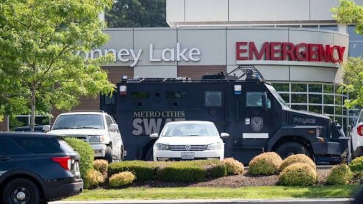 Armored SWAT vehicle parked by a hospital emergency entrance with police cars nearby
