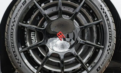 Close-up of a black multi-spoke alloy wheel with a red Bugatti emblem center cap and a Michelin tire visible surrounding it.