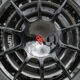 Close-up of a black multi-spoke alloy wheel with a red Bugatti emblem center cap and a Michelin tire visible surrounding it.