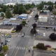 Aerial view of a small town intersection with crosswalks, storefronts, and parked cars in a grid of streets.