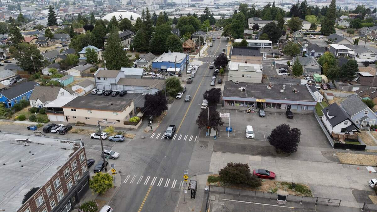 Aerial view of a small town intersection with crosswalks, storefronts, and parked cars in a grid of streets.