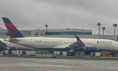 Delta airplane parked at a gate with a jet bridge attached and ground support equipment nearby.