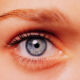 Close-up of a blue eye with long eyelashes and subtle makeup, looking straight ahead.