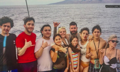 Group of smiling people of various ages posing together on a boat by the sea, with water and distant shore in the background (Woods Family).