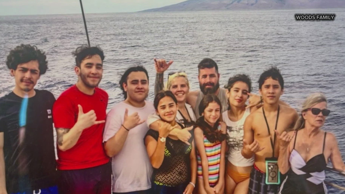 Group of smiling people of various ages posing together on a boat by the sea, with water and distant shore in the background (Woods Family).