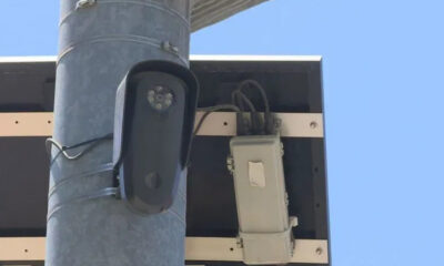 Outdoor surveillance camera mounted on a metal pole beside an electrical box and wiring.