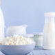 Bowl of cottage cheese with milk bottles in a pale blue kitchen setting.