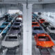 Bright automotive factory with rows of partially assembled cars on an assembly line in a bright, white-washed facility.