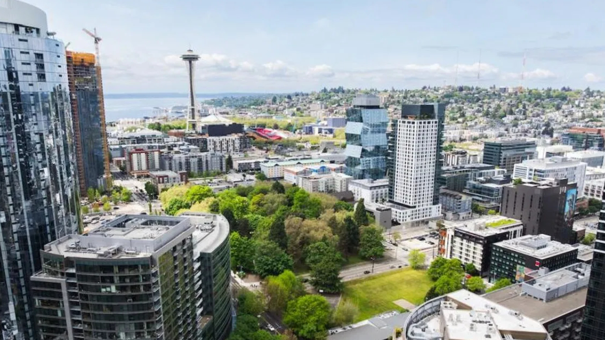 Aerial view of downtown Seattle with the Space Needle in the center, surrounded by glass skyscrapers and a green park in the foreground.
