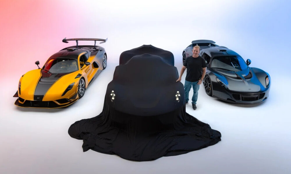 A black car is draped in a cover between a yellow and a blue sports car in a bright studio.