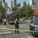 Seattle street scene with police tape and officers guarding a bus near downtown skyline.