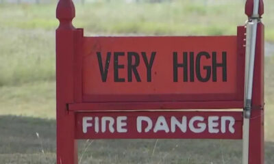 Red warning sign reading 'VERY HIGH' above 'FIRE DANGER' in a grassy outdoor area.