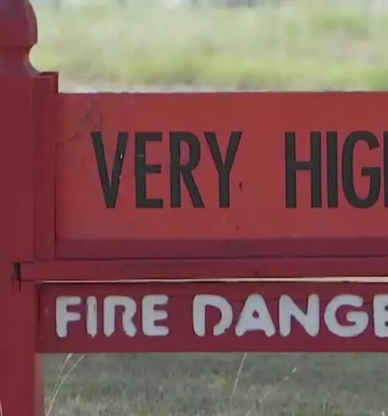 Red warning sign reading 'VERY HIGH' above 'FIRE DANGER' in a grassy outdoor area.