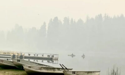Mist-covered lake with several small rowboats lined at the shore and a wooden dock in the background.