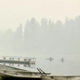 Mist-covered lake with several small rowboats lined at the shore and a wooden dock in the background.