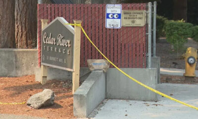 Entrance to Cedar River Terrace with yellow caution tape across a railing and posted safety signs behind a chain-link fence.