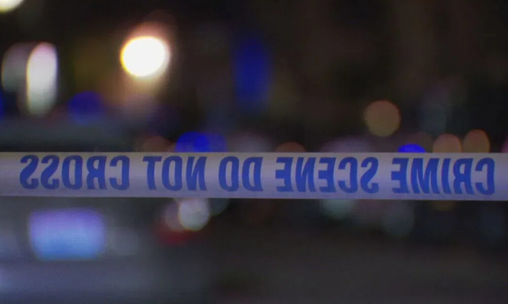 Police tape reading 'CRIME SCENE DO NOT CROSS' across a dimly lit street with blurred city lights in the background.