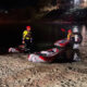 Nighttime riverbank rescue with inflatable boats and two responders in yellow suits and red helmets.