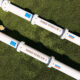 Overhead view of white Nord Stream 1 and Nord Stream 2 gas pipelines lying on green grass, labeled on each segment.