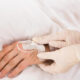 Healthcare worker in gloves securing an IV line on a patient’s hand with tape and tubing visible