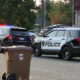 Two Tacoma Police Department SUVs with red and blue lights flashing, parked on a residential street with a trash bin in the foreground.