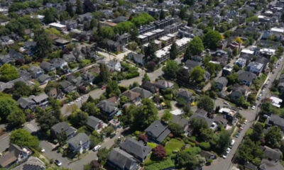 Aerial view of a suburban neighborhood with tree-lined streets and rows of houses in a leafy area of town.