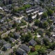 Aerial view of a suburban neighborhood with tree-lined streets and rows of houses in a leafy area of town.