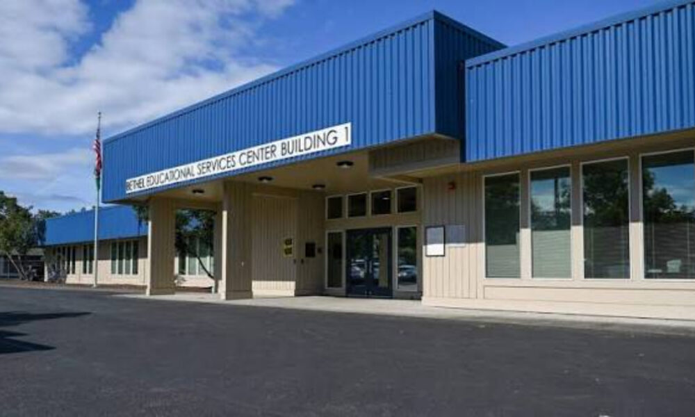 Blue-roofed educational services center building with glass doors and flagpole in front; parking lot visible outside the entrance.