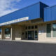 Blue-roofed educational services center building with glass doors and flagpole in front; parking lot visible outside the entrance.