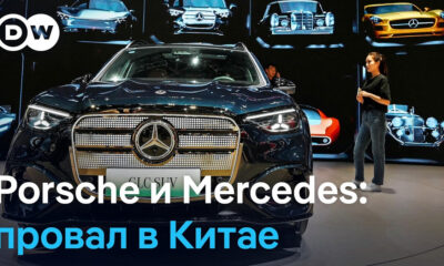 DW logo in the corner; a dark blue Mercedes SUV on a showroom floor with a presenter to the right and a Russian headline about Porsche and Mercedes failing in China