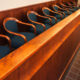 Row of blue upholstered chairs with wooden arms along a glossy wooden barrier in a formal meeting or courtroom setting